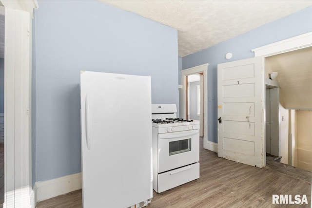 kitchen with white appliances, baseboards, light wood finished floors, and light countertops