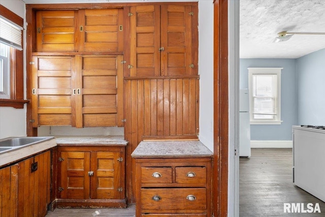 kitchen featuring light countertops, light wood-type flooring, freestanding refrigerator, and brown cabinets