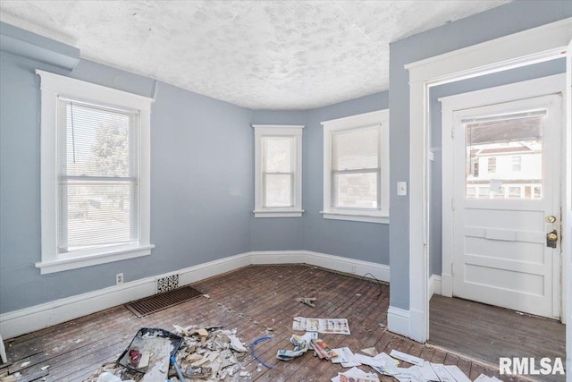 entryway with visible vents, a textured ceiling, baseboards, and wood finished floors