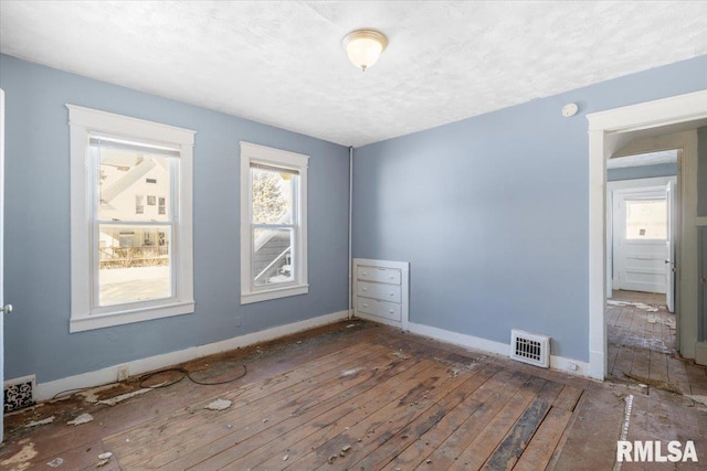 unfurnished room with baseboards, visible vents, and a textured ceiling