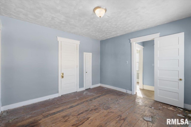 spare room featuring a textured ceiling, dark wood finished floors, and baseboards