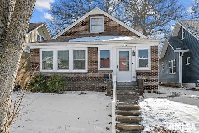 bungalow featuring entry steps and brick siding