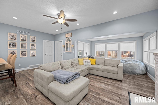 living room with baseboards, visible vents, wood finished floors, and recessed lighting