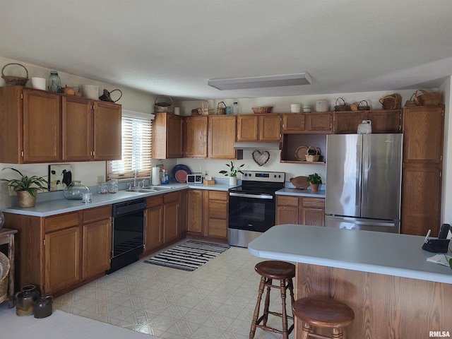 kitchen with light countertops, appliances with stainless steel finishes, brown cabinetry, a sink, and under cabinet range hood