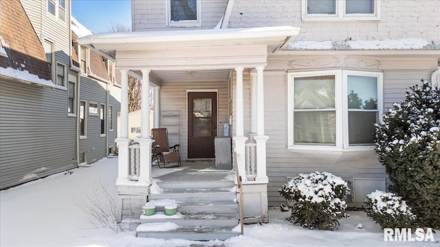 snow covered property entrance with covered porch