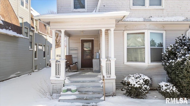 snow covered property entrance featuring covered porch
