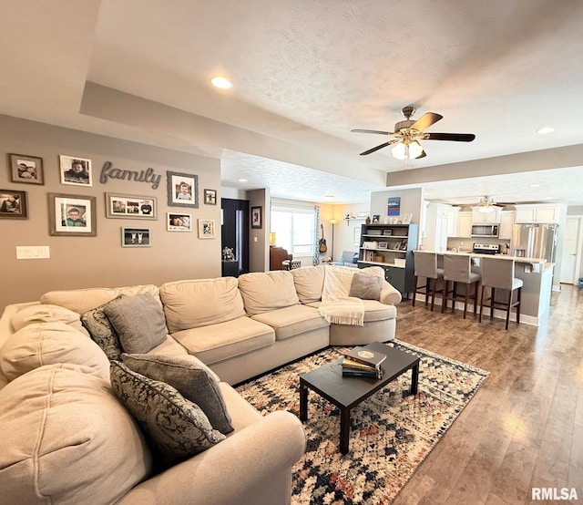 living room featuring ceiling fan, a textured ceiling, wood finished floors, and recessed lighting