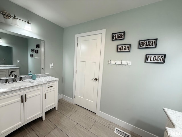 bathroom featuring wood finish floors, visible vents, vanity, and baseboards