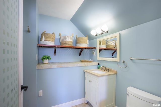 bathroom with lofted ceiling, toilet, and vanity