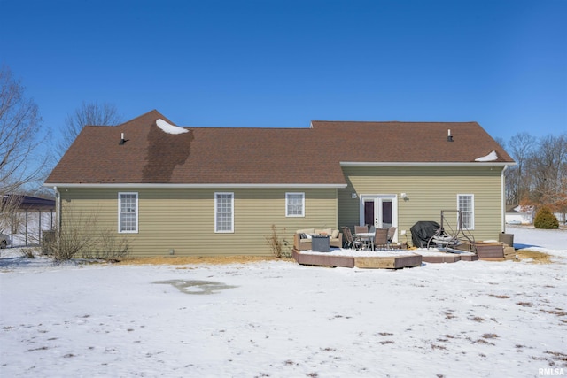 snow covered rear of property with a deck and french doors