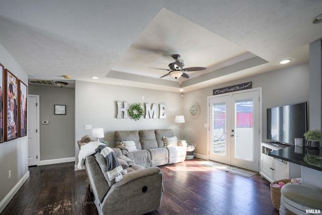 living room featuring baseboards, a tray ceiling, dark wood-type flooring, and french doors