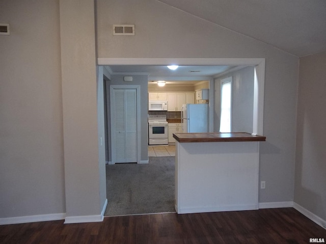 kitchen with lofted ceiling, a peninsula, white appliances, visible vents, and white cabinetry