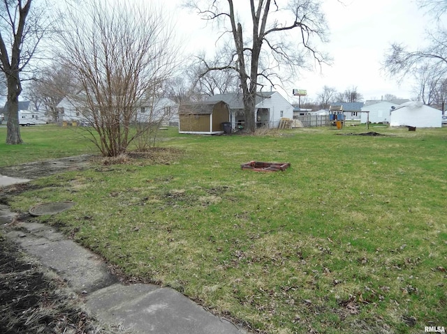 view of yard featuring an outdoor structure, a fire pit, and a shed