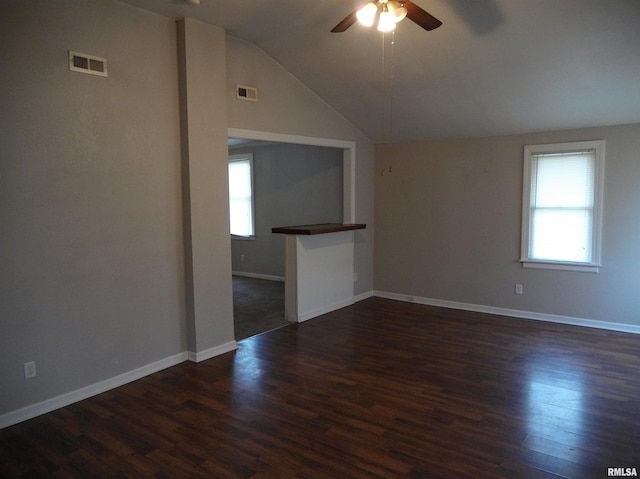 empty room with ceiling fan, visible vents, vaulted ceiling, and dark wood-type flooring