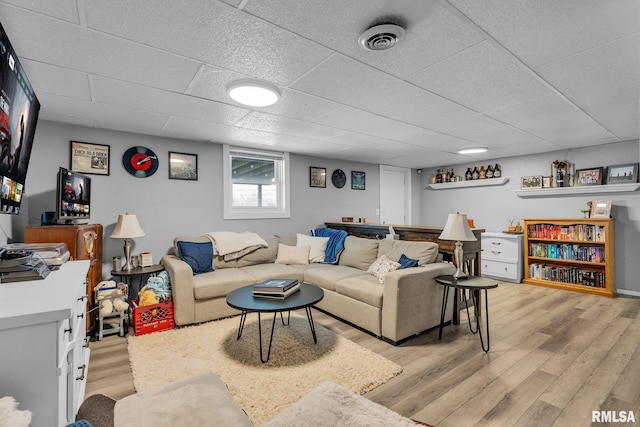 living room with light wood-type flooring, visible vents, and a paneled ceiling