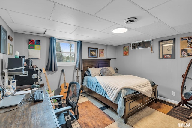 bedroom with baseboards, visible vents, and a drop ceiling