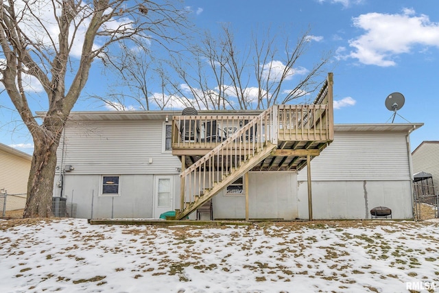 snow covered house featuring a deck, cooling unit, and stairway