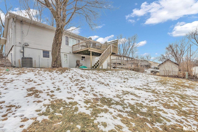 snow covered house with stairway, a wooden deck, and central AC unit