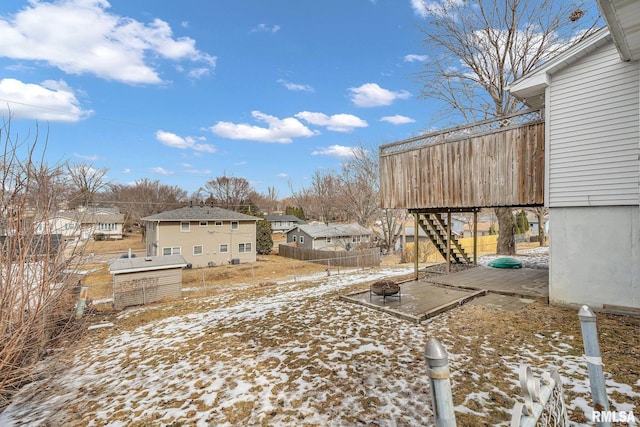 yard layered in snow featuring an outdoor fire pit, a residential view, a wooden deck, and stairs