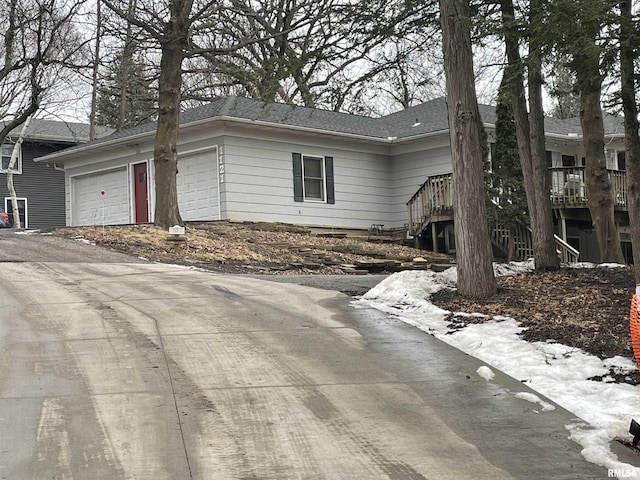 view of snowy exterior with a garage, stairs, and aphalt driveway