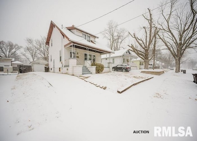 snow covered rear of property featuring a garage and an outdoor structure