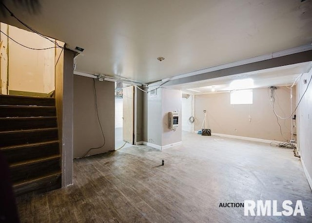 below grade area featuring baseboards, stairway, heating unit, and wood finished floors