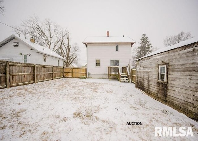 snow covered rear of property featuring a chimney and a fenced backyard