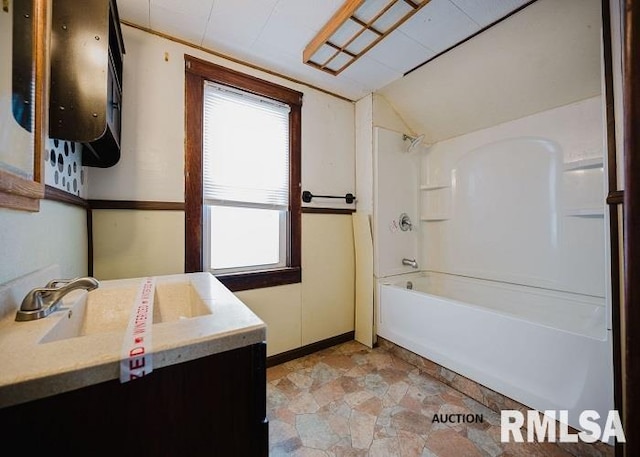 bathroom with stone finish floor, vaulted ceiling, vanity, and bathing tub / shower combination