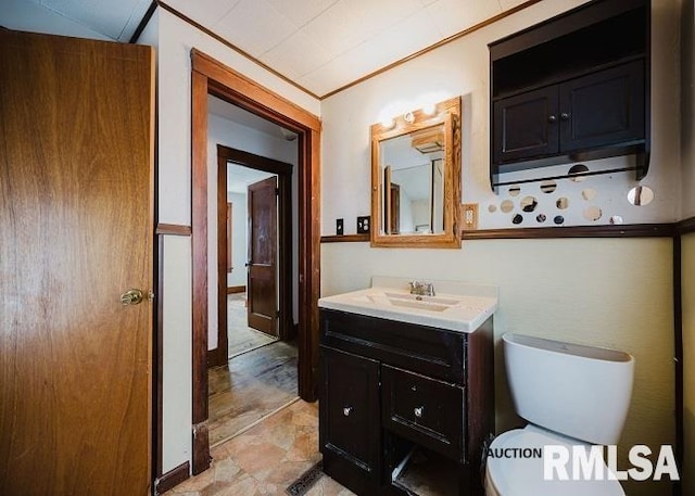 bathroom with ornamental molding, stone finish flooring, vanity, and toilet