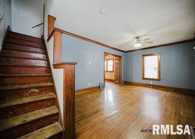 interior space featuring crown molding, baseboards, ceiling fan, and wood finished floors