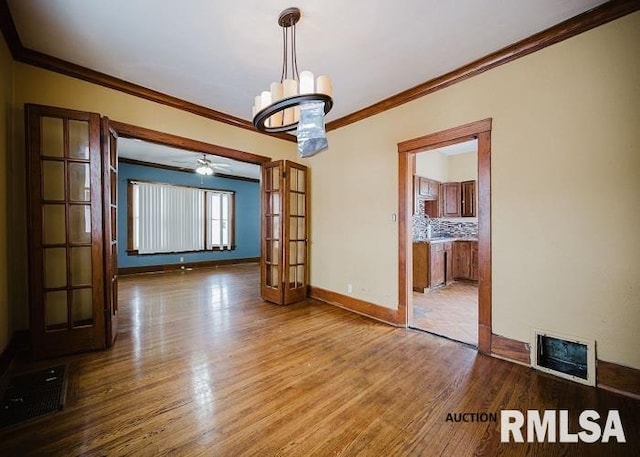 unfurnished dining area with an inviting chandelier, baseboards, visible vents, and wood finished floors