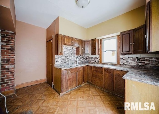 kitchen featuring baseboards, a sink, and decorative backsplash