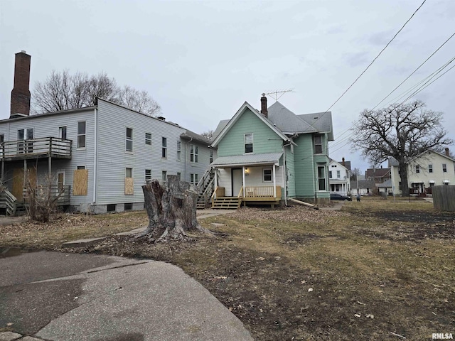 back of property featuring covered porch and a chimney