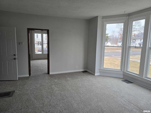 empty room featuring carpet, a textured ceiling, and baseboards