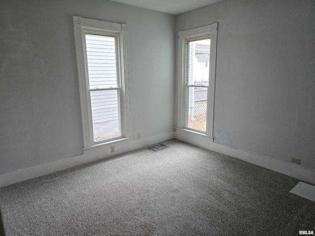 carpeted empty room featuring baseboards and visible vents