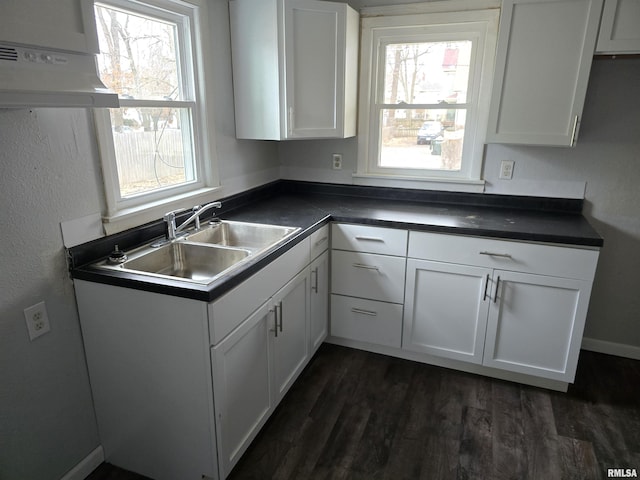 kitchen with dark countertops, plenty of natural light, white cabinetry, and a sink