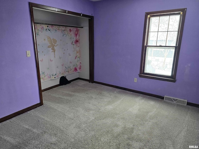 carpeted empty room featuring baseboards and visible vents