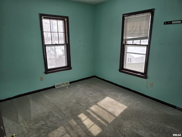 empty room with carpet floors, visible vents, and baseboards