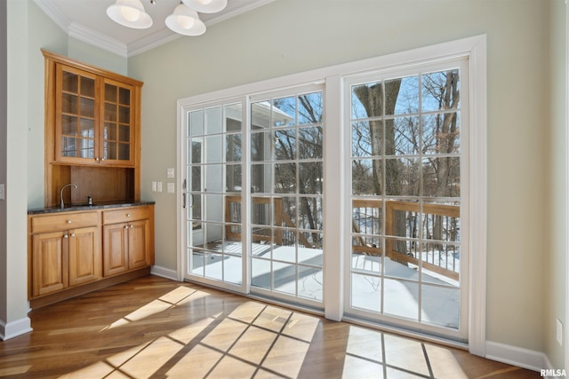 entryway featuring baseboards, crown molding, light wood finished floors, and an inviting chandelier