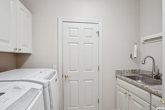 laundry area featuring washing machine and clothes dryer, a sink, and cabinet space