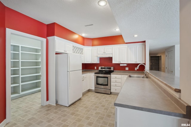 kitchen with freestanding refrigerator, white cabinets, a sink, and stainless steel electric range