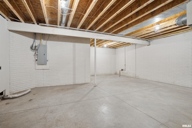 unfinished basement featuring electric panel and brick wall