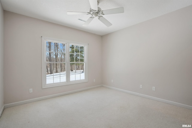 spare room featuring light colored carpet, ceiling fan, and baseboards