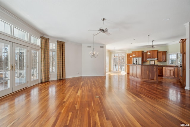 unfurnished living room featuring baseboards, dark wood-type flooring, crown molding, a sink, and ceiling fan with notable chandelier