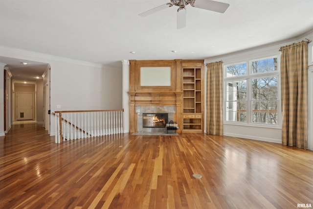 unfurnished living room featuring ornamental molding, wood finished floors, a high end fireplace, and baseboards