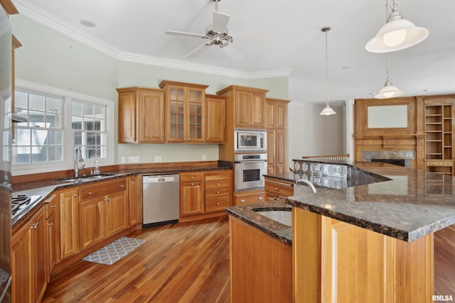 kitchen featuring appliances with stainless steel finishes, a kitchen island with sink, a sink, and hanging light fixtures