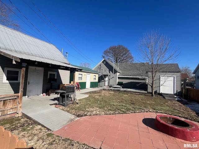 rear view of property with an outdoor fire pit, metal roof, an outbuilding, fence, and a patio area