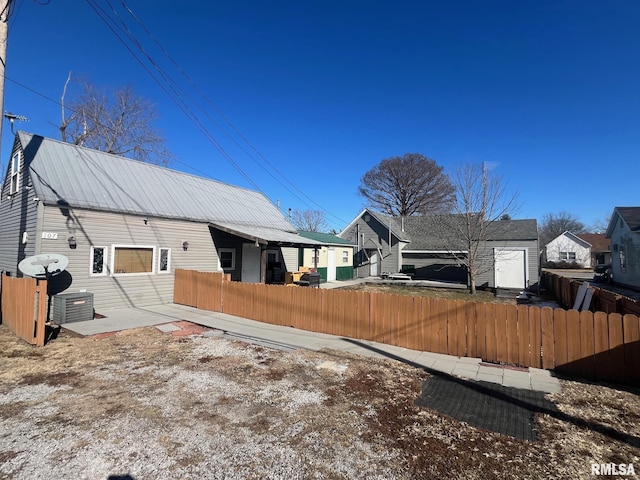 rear view of house featuring central air condition unit, fence, and metal roof