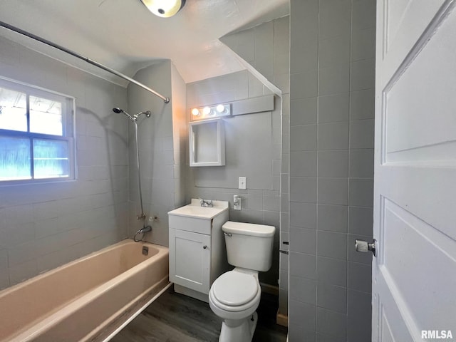 full bathroom with bathing tub / shower combination, toilet, wood finished floors, vanity, and tile walls