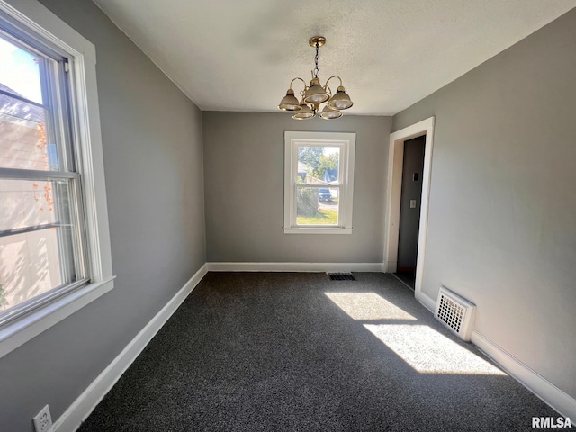 unfurnished room featuring carpet, visible vents, a notable chandelier, and baseboards